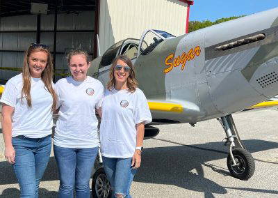Three chapter members in front of a vintage aircraft