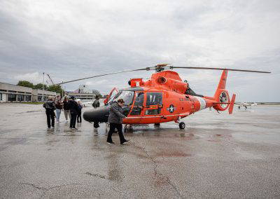 Visitors walk out to the orange Coast Guard helicopter