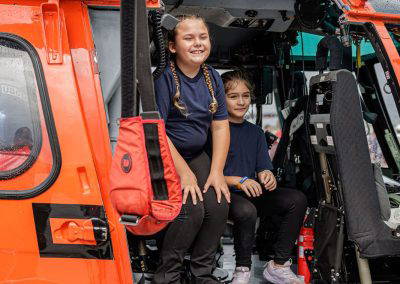 Two girls sit in the doorway of the Coast Guard helicopter