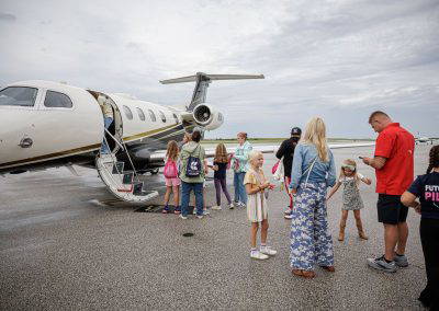 Families walk up to a business jet with its door open