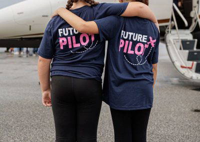 Two girls in Future Pilot shirts walk toward a business jet