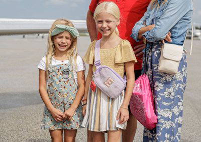 A family poses on the ramp in front of a jet