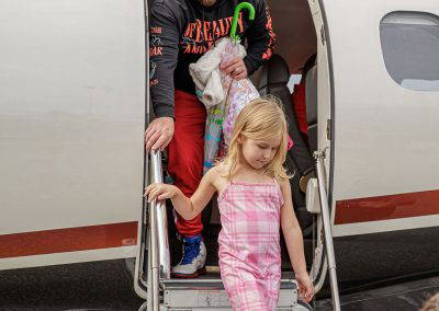 A girl steps down the stairs of a business jet