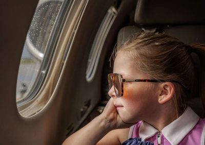 A girl in sunglasses looks out the window of a business jet