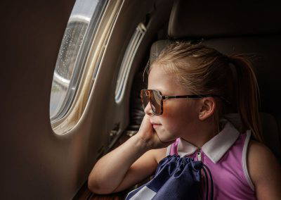 A girl gazes out the cabin window of a jet