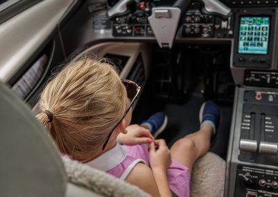 A girl explores the cockpit controls of a jet