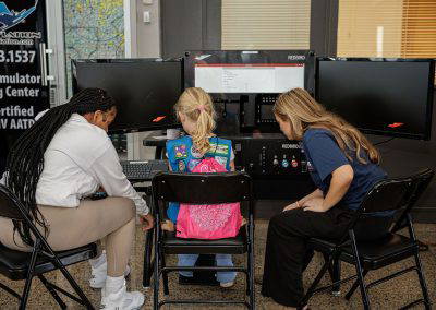 Girls try a flight simulator with a volunteer