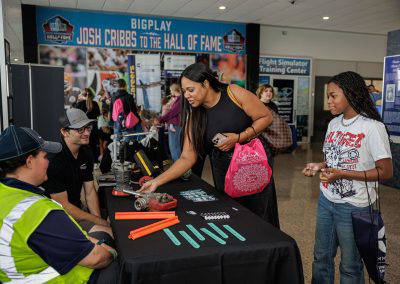 A girl tries an activity at an exhibitor table
