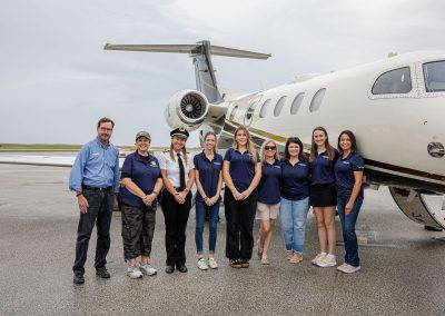 Women in Aviation Cleveland volunteers and pilots pose in front of a jet