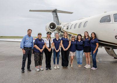 Chapter volunteers and pilots pose together beside a jet