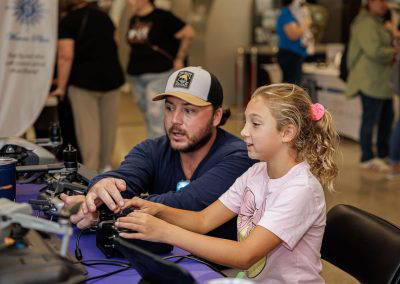 A girl tries a drone controller with a volunteer