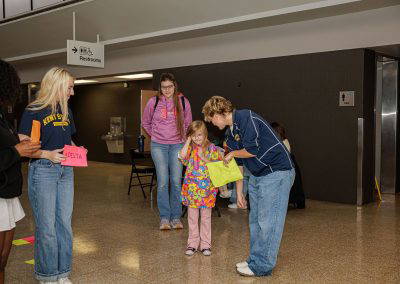 Volunteers cheer on girls playing a floor game