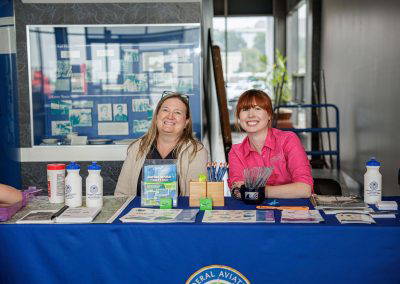 Two volunteers smile behind an aviation information table