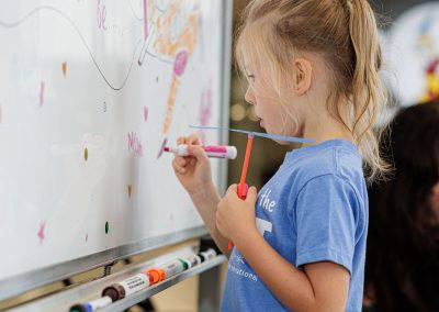 A girl draws on the When I Grow Up whiteboard