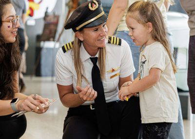 A pilot kneels to talk with a young girl