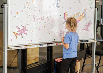 A girl writes on the colorful When I Grow Up board
