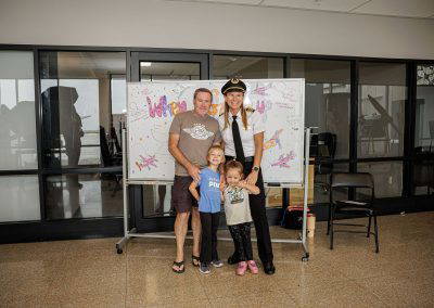 A family poses with a pilot in front of the When I Grow Up board