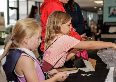 Girls work on a hands-on craft at an activity table