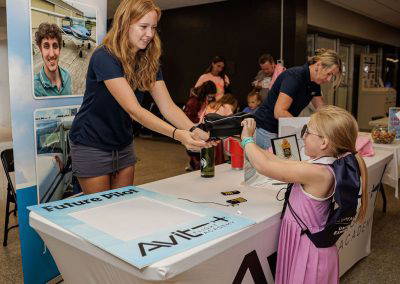 A volunteer shows a girl an activity at the Avit table