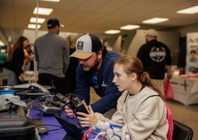 A volunteer helps a girl try a drone controller